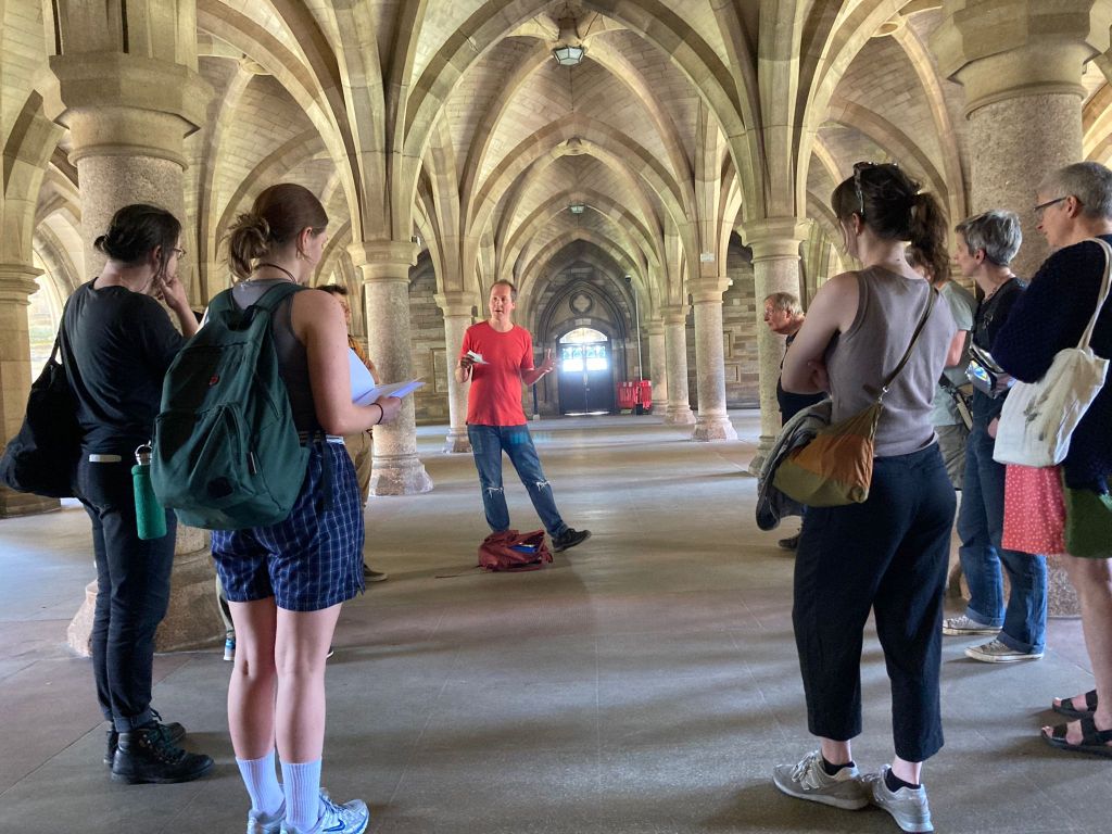 A group of people listening to a tour in the university cloisters